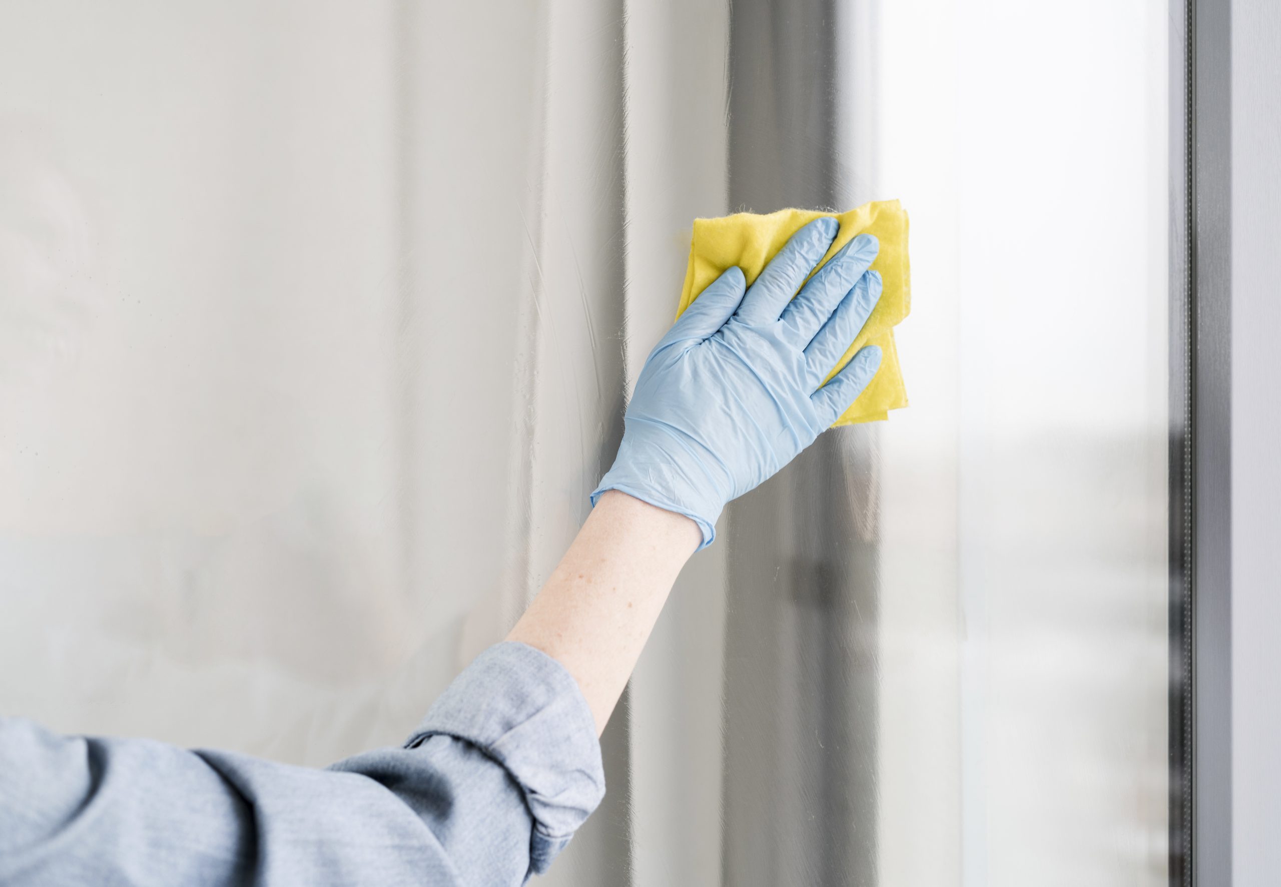 woman-with-rubber-glove-wiping-window